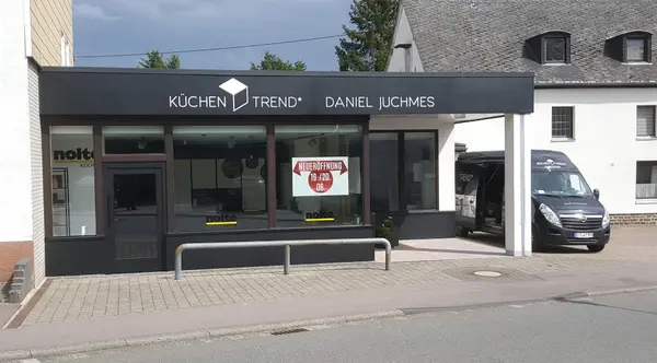 Modernes Küchenstudio mit großer Glasfront und Werbeplakat zur Neueröffnung in Stadtlage.