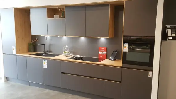 Moderne Einbauküche mit grauen Fronten, Holzarbeitsplatte und integriertem Backofen.