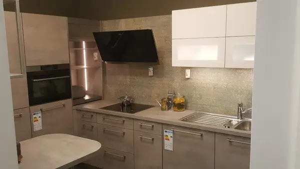 Moderne Einbauküche mit hellen Fronten, Elektrogeräten und Edelstahlspüle im Küchenstudio.