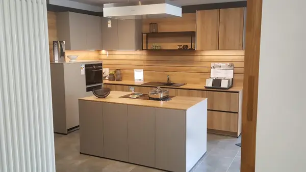 Moderne Einbauküche mit Kücheninsel, Holzfronten und grauen Schränken in heller Umgebung.