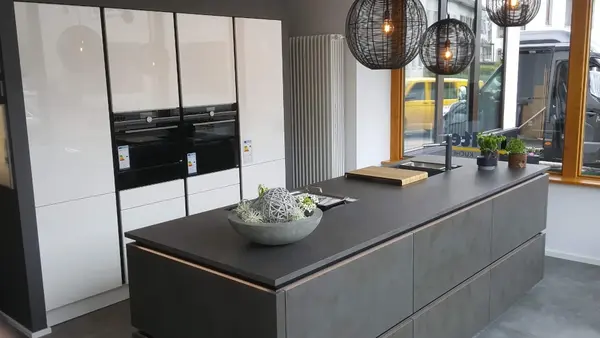 Moderne Designküche mit Kochinsel, Hängelampen und großem Fenster für Tageslicht.