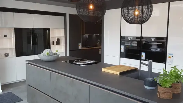 Moderne Designküche mit Kochinsel, Einbaugeräten, Hängelampen und frischen Kräutern.